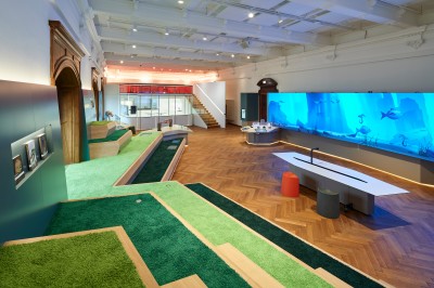 : Bright exhibition room with interactive area, large screens showing underwater scenes, and green play surfaces. (AI-generated alt-text, generated with GPT-4.1-mini)